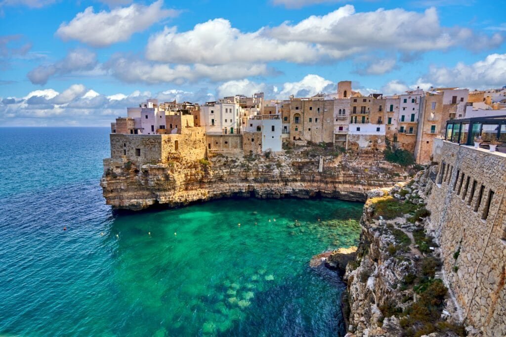 Picturesque Mediterranean coastal town with colourful buildings on cliffs overlooking turquoise sea.
